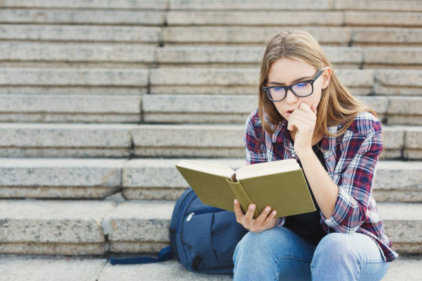 istock Young woman reading book on university stairs 917637688