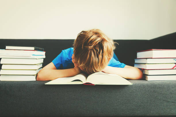 istock little boy tired stressed of reading, doing homework 917638736