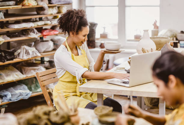 istock Woman Holding Pottery Craft, Looking at Laptop 917639062