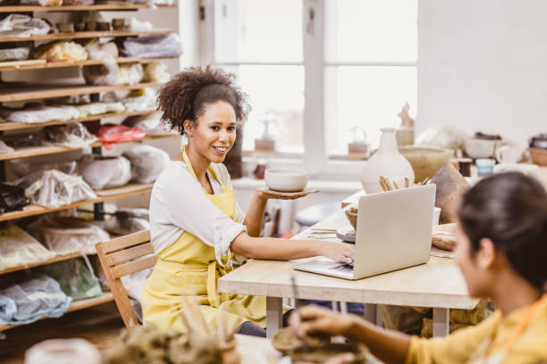 istock Woman Holding Pottery Craft, Looking at Laptop 917639086