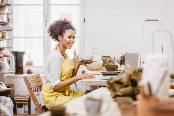 istock Woman Holding Pottery Craft, Looking at Laptop 917641132