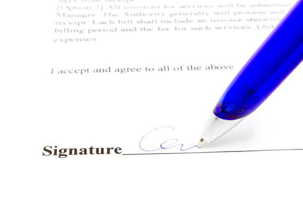 Blue pen writing signature on white paper. A person is signing a contract here above the black line beneath the text on this form. Usually people sign to enforce their agreement concerning a financial transaction. That could be a sale, buying or selling something for money to someone else.