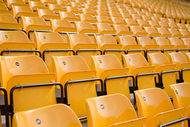 Linhas de cadeiras vazias no Estádio desportivo amarelo - fotografia de stock