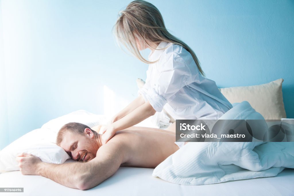 Young woman massage her husband in bed 20-29 Years Stock Photo