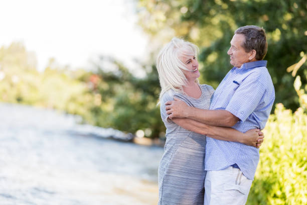 istock Elderly marriage hugging by the lake. 917646610
