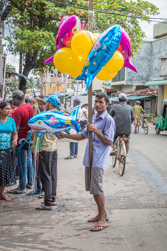 Negombo, Sri Lanka - December 20, 2017: Man selling balloons in front of a market.