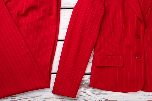 Feminine red classic suit, wooden background.