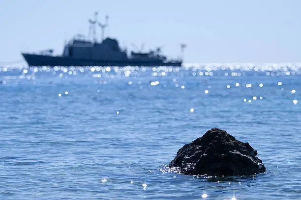 Bid stone on sea and escort vessel on background