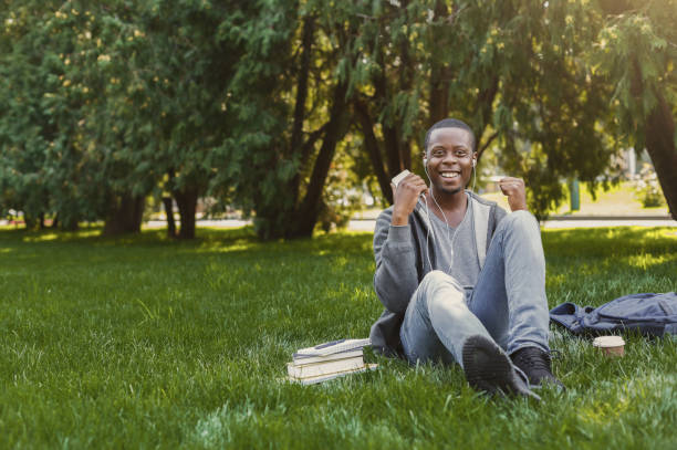 istock Happy successful student sitting on grass listening to music 917660254