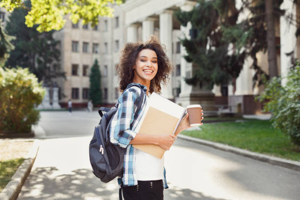 istock Student girl with backpack and workbooks at university building background 917661226