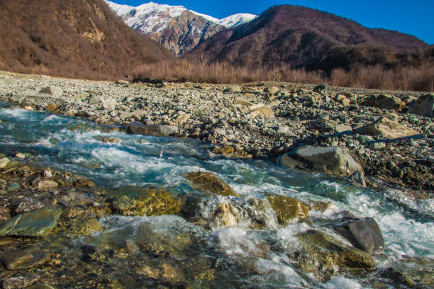 istock Stream river and mountain landscape. Snowy peak in distance 917664630