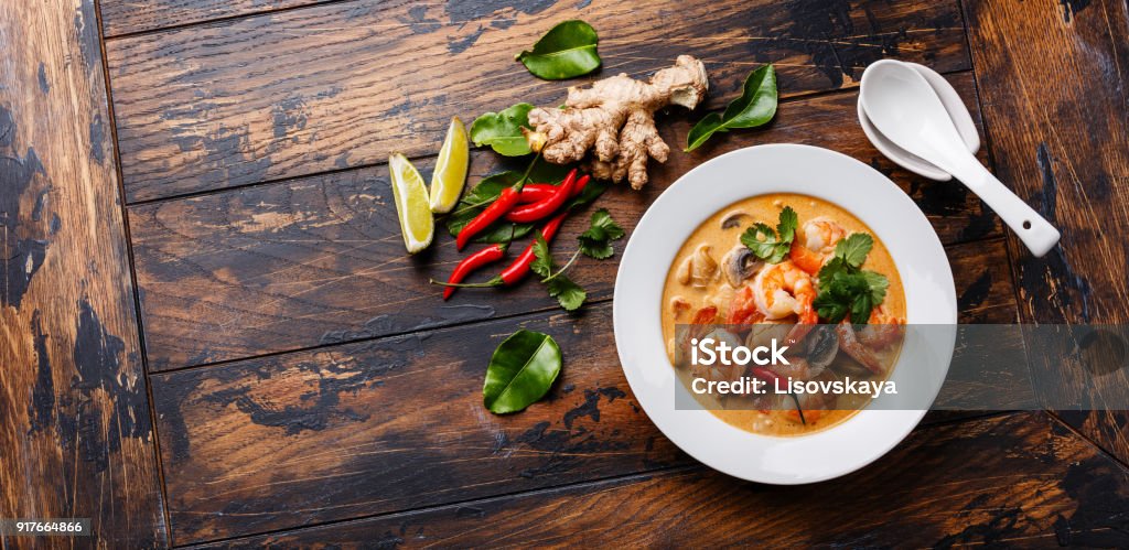 Tom Yam kung Spicy Thai soup Tom Yam kung Spicy Thai soup with shrimp, seafood, coconut milk and chili pepper in bowl on wooden background copy space Thai Food Stock Photo