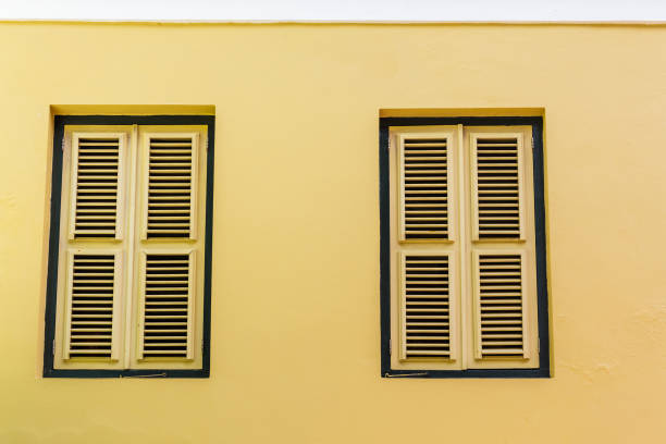 istock Two Yellow Shutters in Yellow Stucco Wall 917667902
