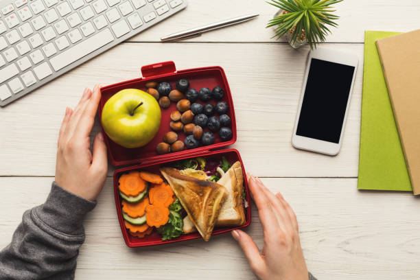 istock Woman eating healthy sandwich from lunch box at her working table 917669566