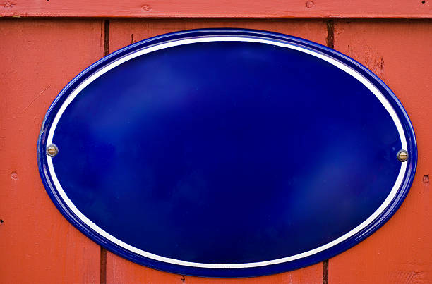 Copy space on an enamel blue oval sign on a red wood wall.