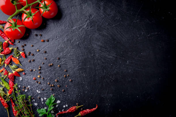 istock Fresh cherry tomatoes on a black background with spices with slate plate. Top view with copy space. 917683408