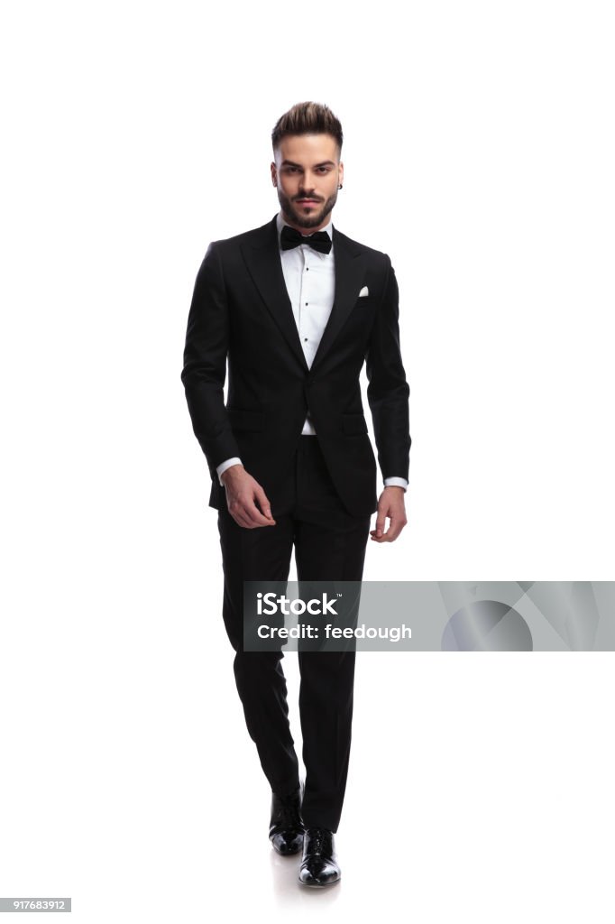 happy young male fashion model in tuxedo is walking happy young male fashion model in tuxedo is walking on white background Men Stock Photo