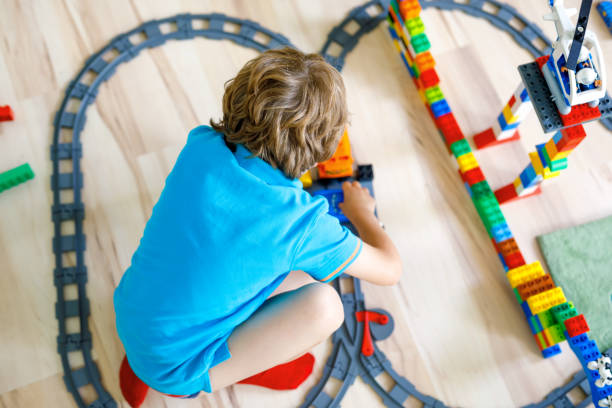 istock little blond kid boy playing with colorful plastic blocks and creating train station 917685056