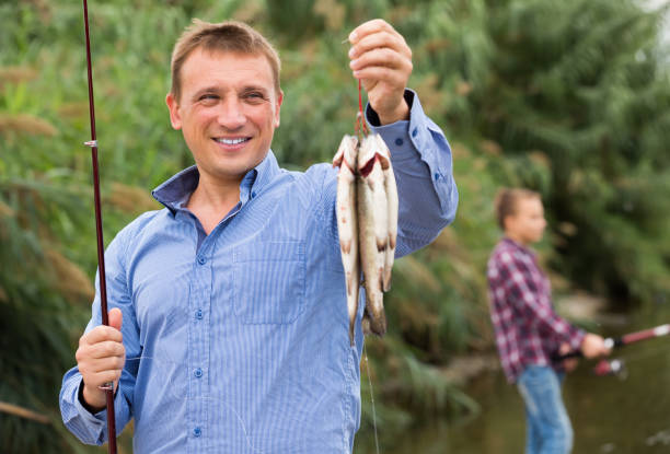 istock Fisherman holding catch freshwater fish on river 917685402