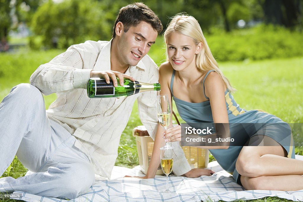Giovane Coppia felice festeggiare con champagne al picnic - Foto stock royalty-free di Picnic