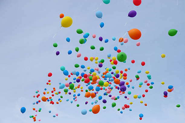 Many colored balloons fly into sky stock photo