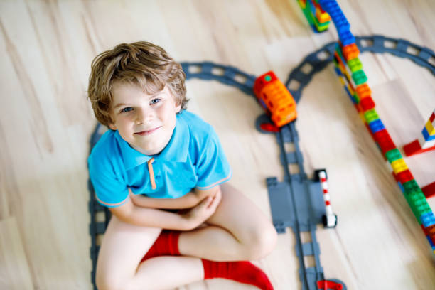 istock little blond kid boy playing with colorful plastic blocks and creating train station 917691114