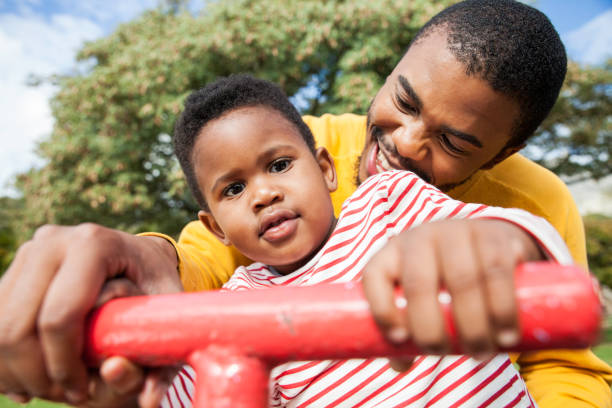 istock Father holds his son's hand while playing on a seesaw at the park. 917695314