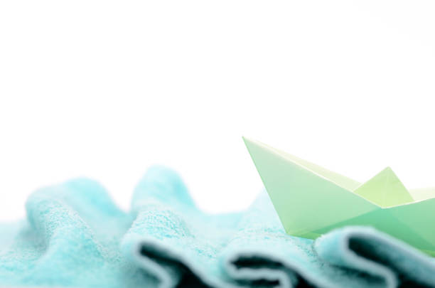 istock Paper ship sails on woolen fabric waves , hand crafted paper boat on fabric waves. 917697042