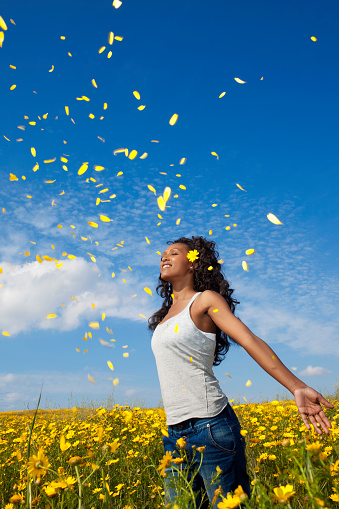 Young lady enjoying yellow petals fall. Blue sky background.