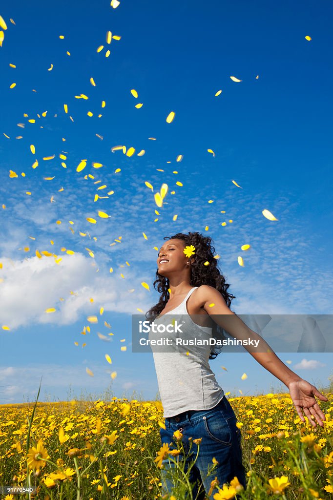 Yellow petals fall Young lady enjoying yellow petals fall. Blue sky background. Spreading Stock Photo