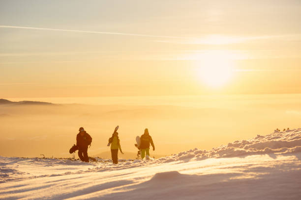 tre amici con sci e snowboard sulle montagne al tramonto - snowboarding friendship snow winter foto e immagini stock