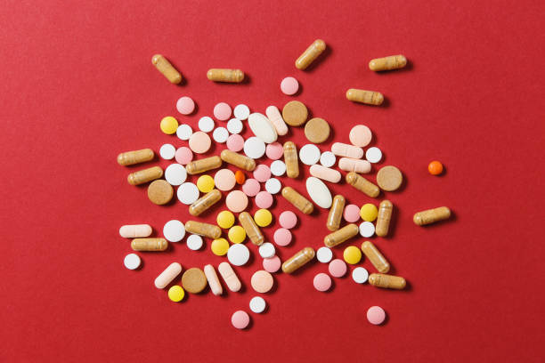 istock Medication white colorful round tablets arranged abstract on red color background. Aspirin, capsule pills for design. Health, treatment, choice healthy lifestyle concept. Copy space advertisement. 917722676