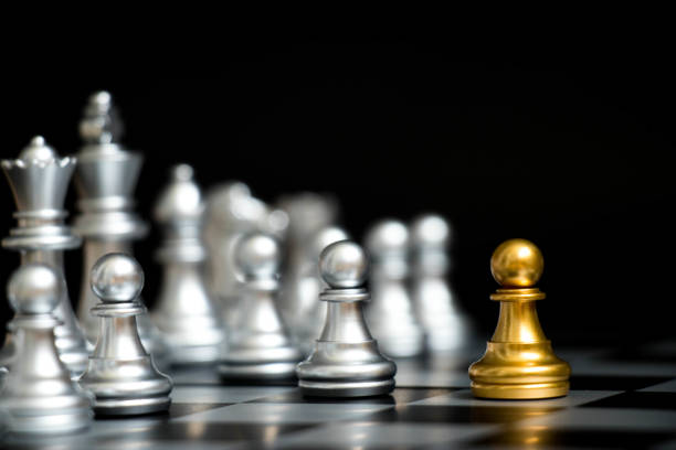 istock Gold pawn in chess game face with the another silver team on black background (Concept for company strategy, business victory or decision) 917725574