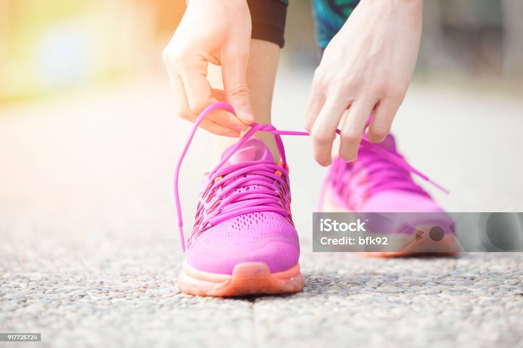 Young woman runner tying shoelaces Power Walking Stock Photo