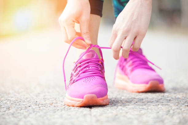 Young woman runner tying shoelaces Young woman runner tying shoelaces power walking photos stock pictures, royalty-free photos & images