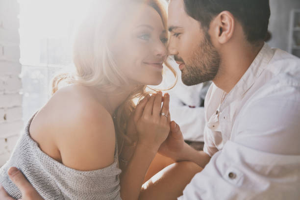 Real love. Beautiful young couple bonding and smiling while sitting in the bedroom anniversary photos stock pictures, royalty-free photos & images