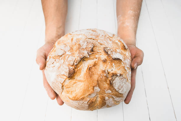 istock Closeup of male hands put fresh bread on an old rustic table on black background with copy space for your text 917729588