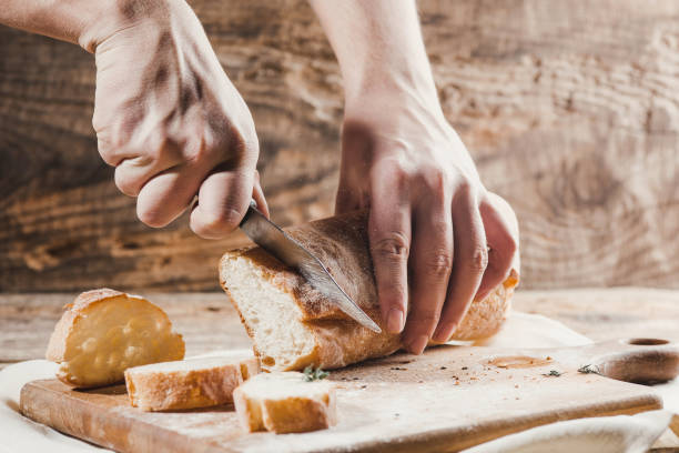 istock Whole grain bread put on kitchen wood plate with a chef holding gold knife for cut 917729970