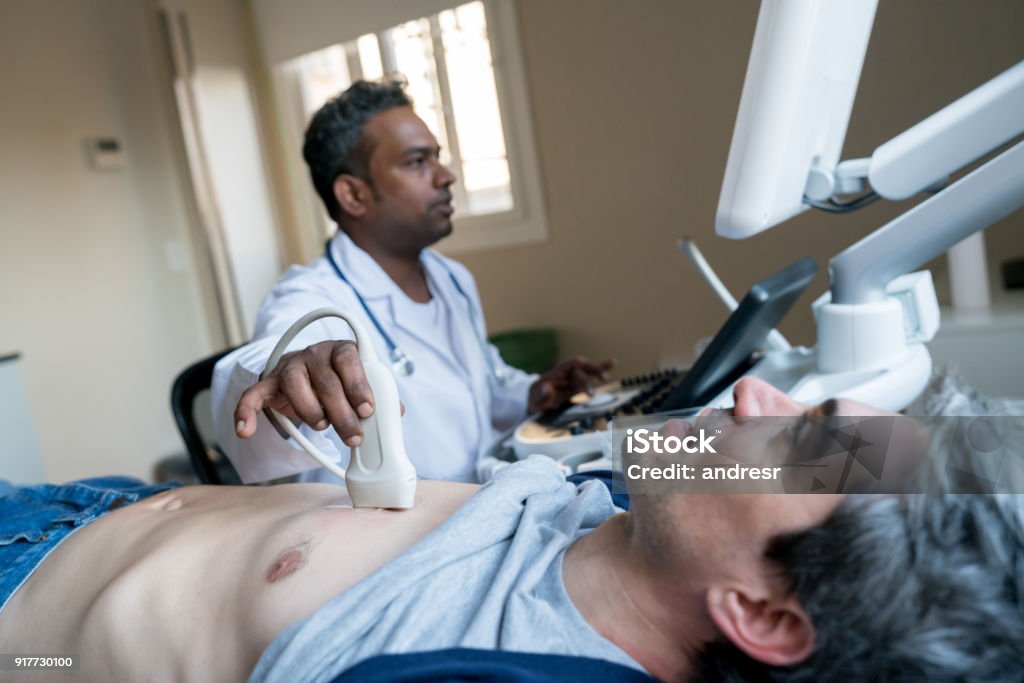 Indian doctor doing a heart ultrasound to a middle aged male patient Indian doctor doing a heart ultrasound to a middle aged male patient at the hospital Heart - Internal Organ Stock Photo