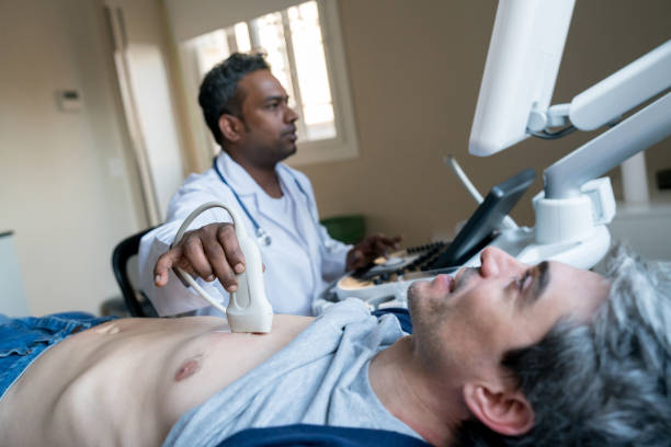 Indian doctor doing a heart ultrasound to a middle aged male patient Indian doctor doing a heart ultrasound to a middle aged male patient at the hospital diagnostic medical tool stock pictures, royalty-free photos & images