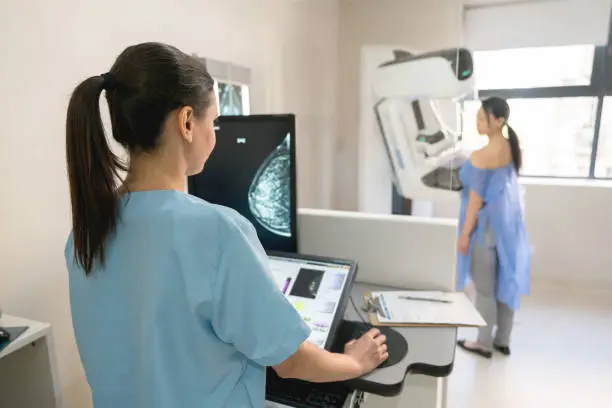 Unrecognizable nurse taking a mammogram exam to an adult patient at the hospital