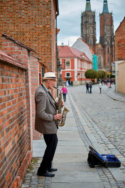 street musician with saxophone on pedestrian tumski bridge with cathedral of st. john the baptist on the background. wroclaw, poland. - medieval autumn cathedral vertical imagens e fotografias de stock