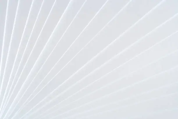 Photo of White geometric pattern of clean paper sheets, spaced as fan.