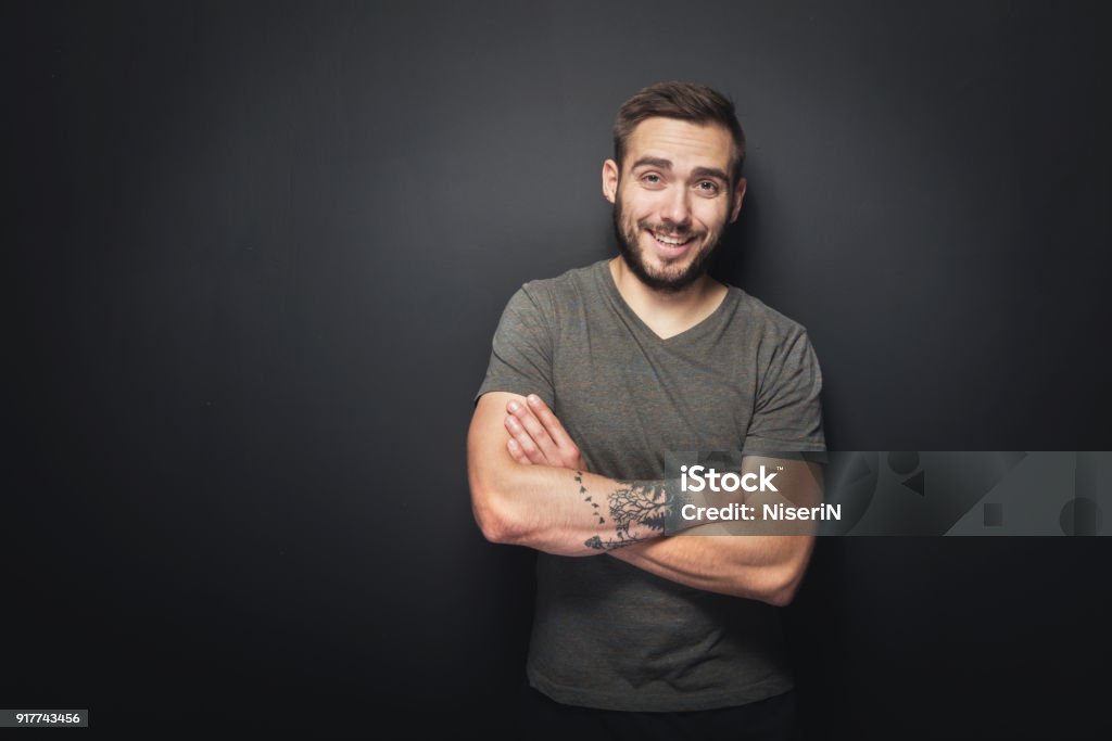 Joyful, handsome man on a black background Portrait of a man standing in front of a black background with his arms crossed and a smile on his face. Men Stock Photo