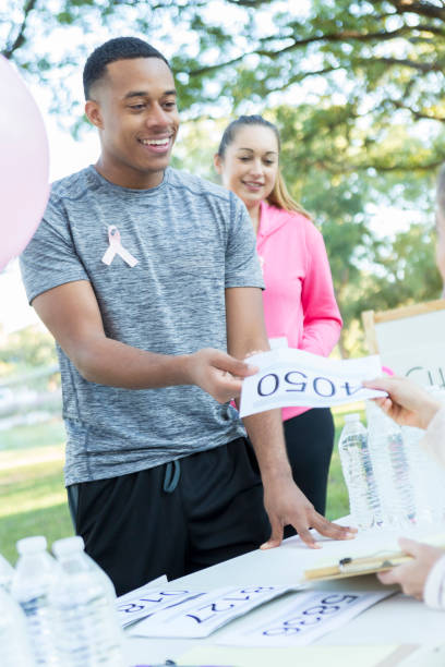 istock Young man distributes sports bibs before breast cancer race 917743700