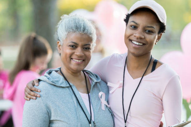 donna anziana e figlia sorridono per la macchina fotografica in gara per la cura - cancer women womens issues friendship foto e immagini stock