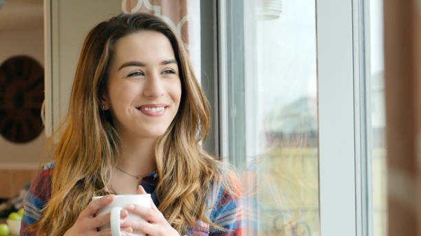 istock Beautiful young woman drinks coffee at home 917744182