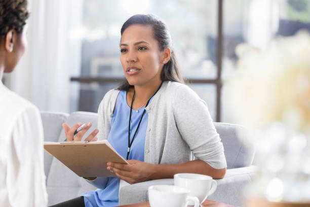 Female psychiatrist discusses something with female patient Confident African American female mental health professional gestures as she talks with an unrecognizable female patient. doctor utensils stock pictures, royalty-free photos & images