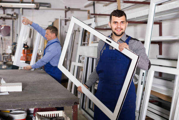 Production workers in coverall with different   finished PVC profiles and windows at factory