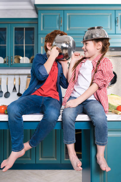 istock adorable barefoot children having fun with utensils while sitting on kitchen table 917750364
